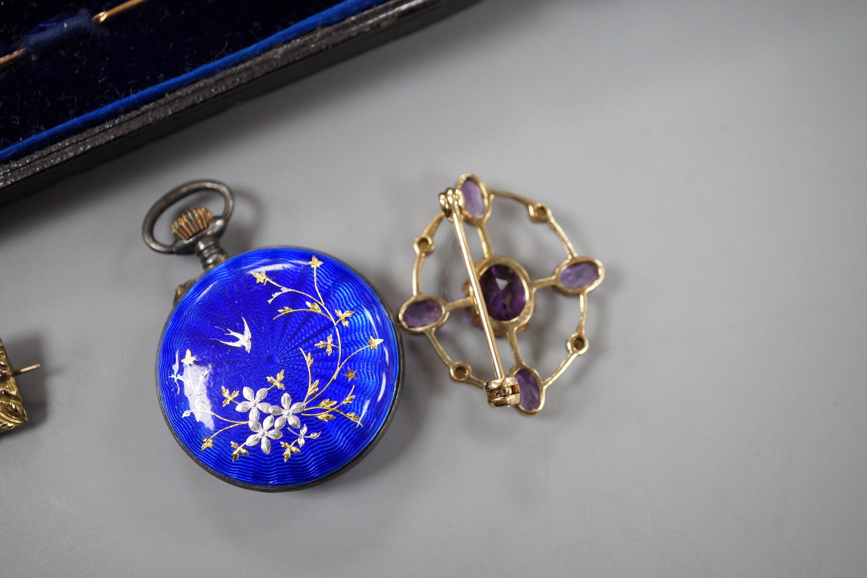 An early 20th century yellow metal, amethyst and seed pearl set oval brooch, 28mm, a Victorian yellow metal mourning brooch, a similar yellow metal and diamond set stick pin, a white metal and enamel fob watch(a.f.) and